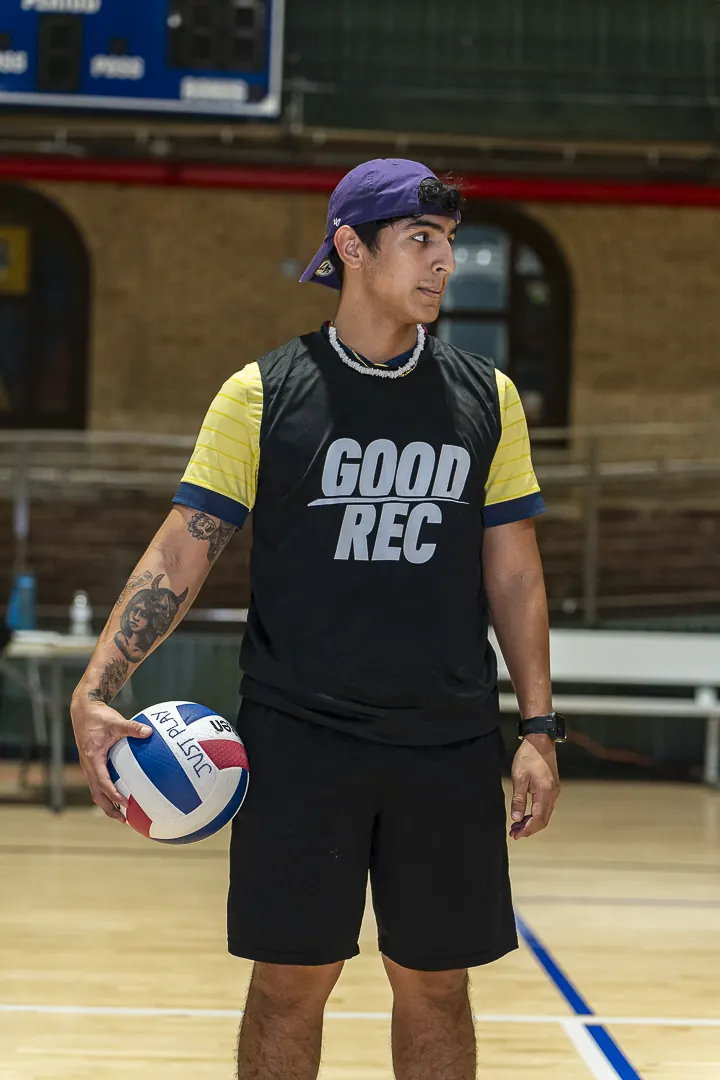 A player in a GoodRec bib holding a volleyball on an indoor court