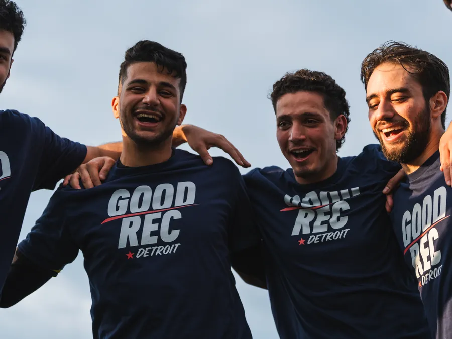 Four players in GoodRec shirts laughing with arms round each other
