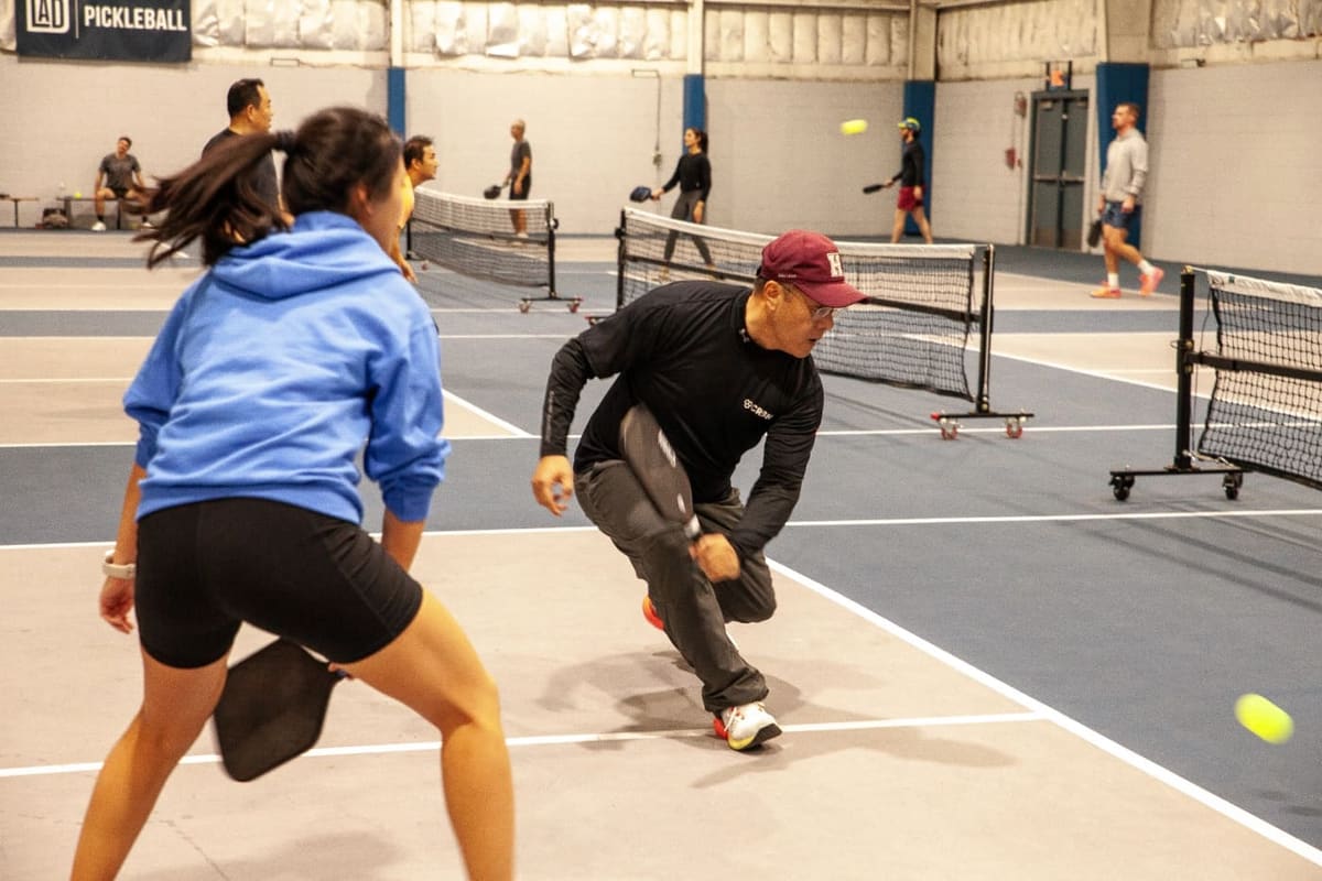 An adult pickleball league player reaches for the ball in a GoodRec Ladder League
