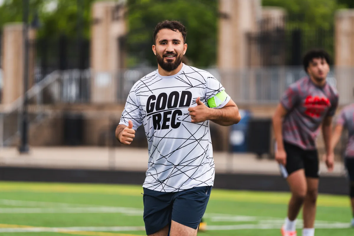 A player in a GoodRec shirt smiling and giving a thumbs up on the field