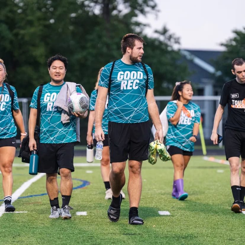Players in GoodRec shirts walking onto the field, one carrying a ball