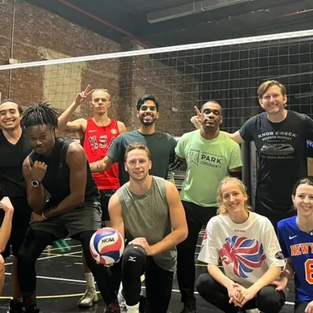 A group of players posing together by the net after an indoor GoodRec volleyball game