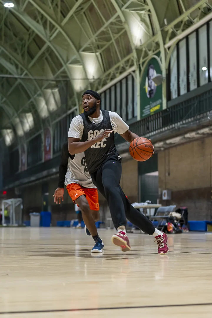 A player in a GoodRec bib driving the ball up an indoor court