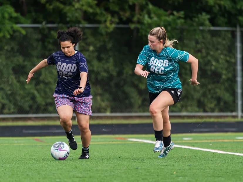 Two players in GoodRec shirts challenging for the ball