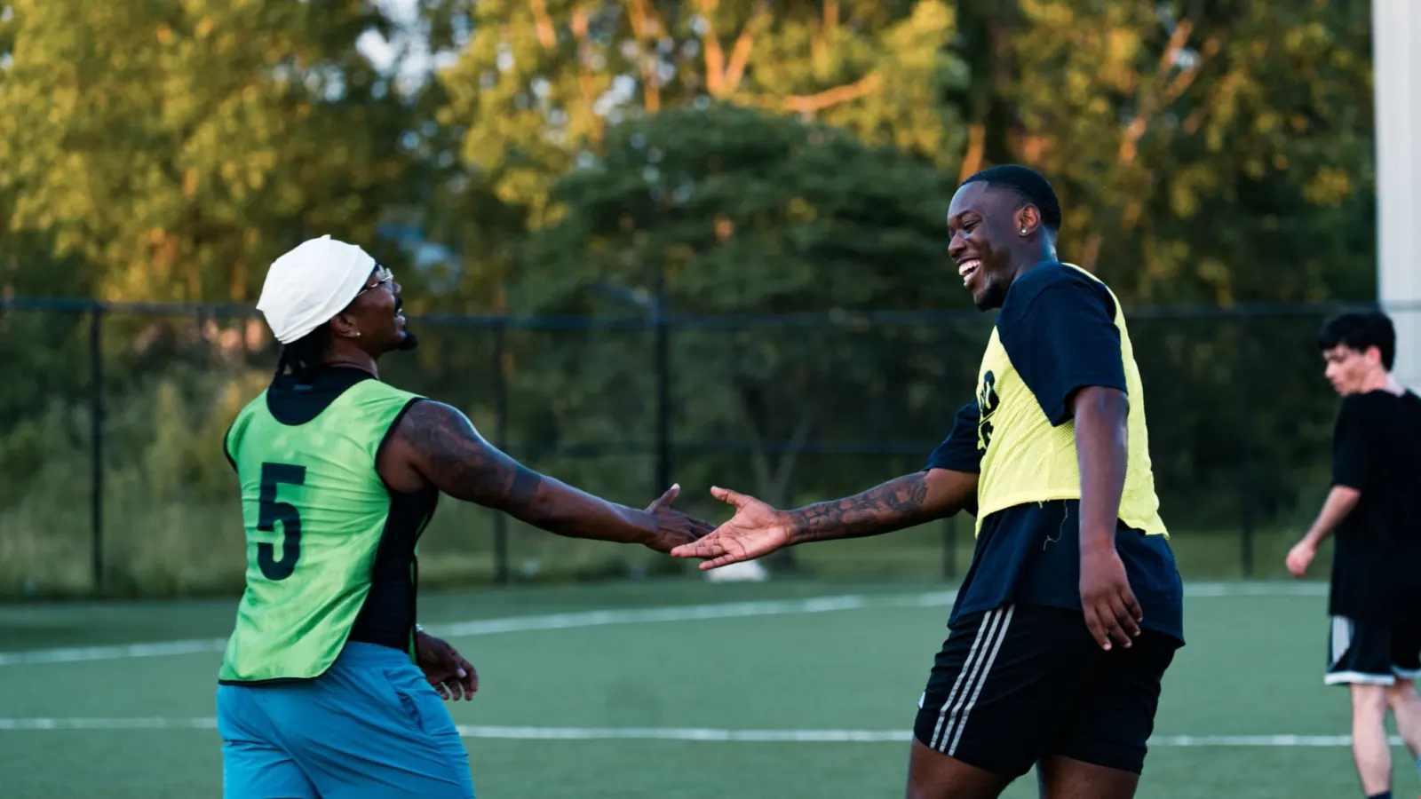 Two players in GoodRec bibs high-fiving and laughing after a pickup soccer game